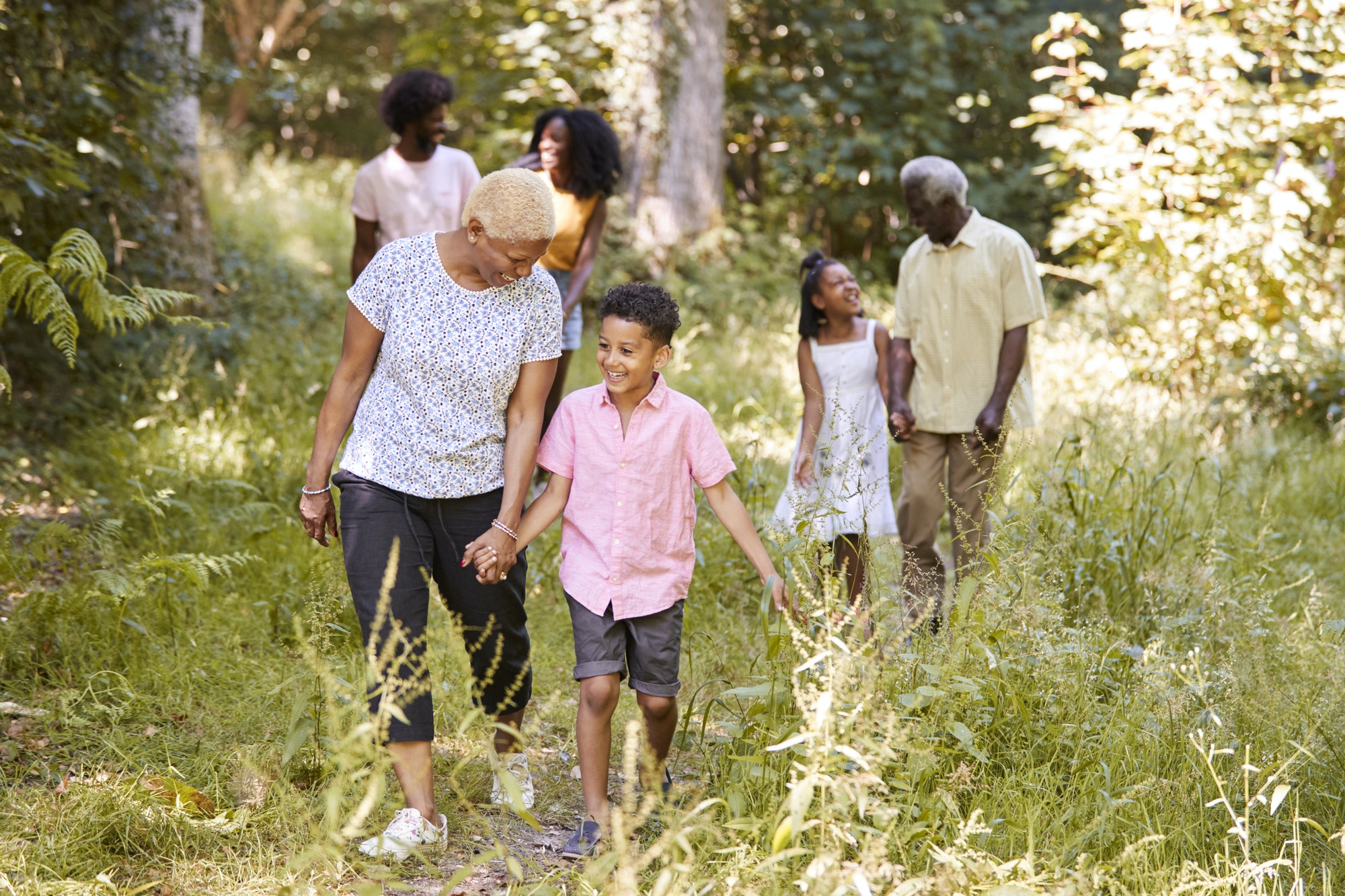 Black grandma walking with grandson and family, full length